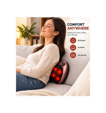 A woman reclining on a light gray sofa with a rose gold massage pillow behind her neck, showing glowing red massage nodes. Text on the right reads 'COMFORT ANYWHERE' with icons for 'At Home', 'At Work', and 'On the Go'.